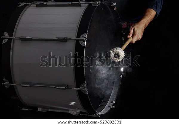 Drum sticks hit on the bass drum in black background,\
close-up, low key