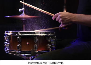 Drum sticks hitting snare drum with splashing water on black background under studio lighting close up. - Powered by Shutterstock