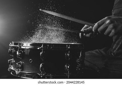 Drum sticks hitting snare drum with splashing water on black background under stage lighting. - Powered by Shutterstock