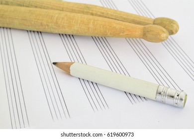 Drum Sticks, A Pencil And A Music Sheet On A Desk In A Classroom. Empty Copy Space For Editor's Text.