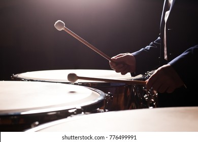 Drum sticks striking in timpani in dark tones