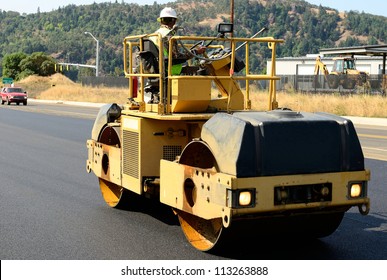 Drum tandem vibratory rollers compacting down a fresh layer of paving on a new road interchange project