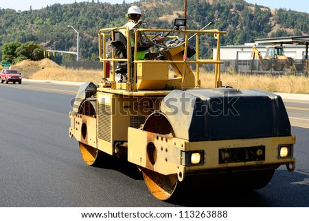Drum tandem vibratory rollers compacting down a fresh layer of paving on a new road interchange project