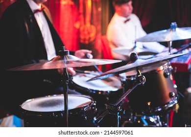 Drummer percussionist performing on a stage with drum set kit during jazz rock show performance, with a band performing in the background, drummer point of view
