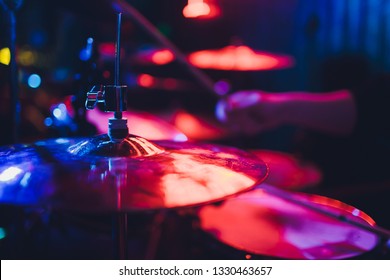 Drummer playing drum set at concert on stage. Music show. Bright scene lighting in club,drum sticks in hands.