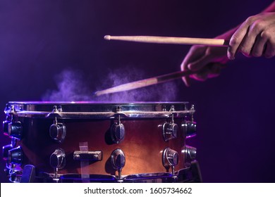 The drummer plays the drums. Beautiful blue and red background, with rays of light. Beautiful special effects smoke and lighting. The process of playing a musical instrument. The concept of music.