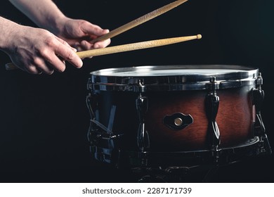 Drummer using drum sticks hitting snare drum with splashing water.