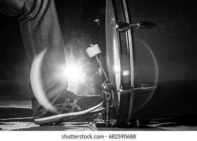 The drummer's foot wears sneaker is playing bass drum pedal in low light background, black and white - Powered by Shutterstock