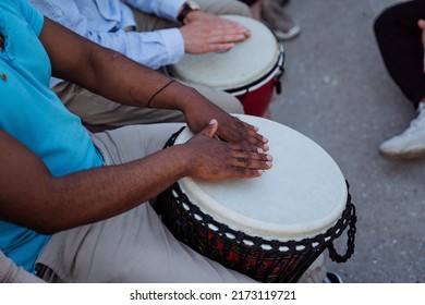 Drumming Close-up, A Black Guy Beats The Rhythm On A Djmba, A Street Musician Performing In Front Of People, Percussion Sounds Of Nature. High Quality Photo