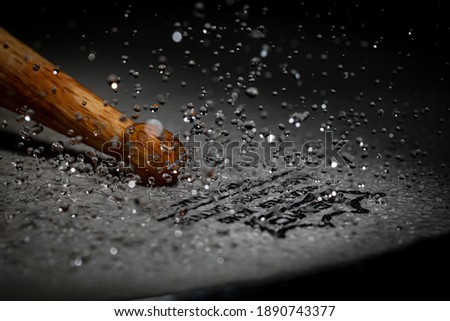 Drumstick beating down on Drum with water
