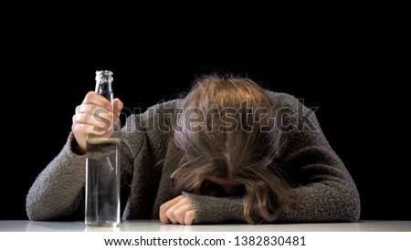 Drunk addicted female holding vodka bottle sitting table, problem hopelessness