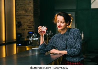 Drunk Brunette Student Woman Alone In Depressed Face Expression Looking Thoughtful In Pub Or Night Club. Desperate Girl Binge Drinking To Forget Problems Glass Of Scoth Whiskey Alcohol.