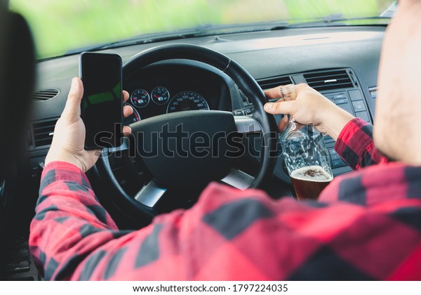 Drunk driver behind the wheel. Man drinking\
in the car and talking on the phone. Alcohol problem. Dangerous\
problem. Accident\
possibility.