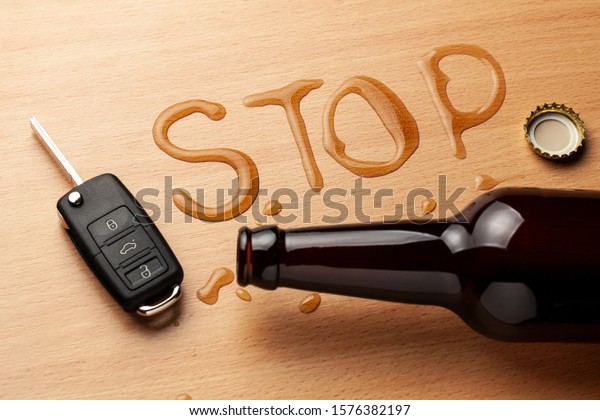 Drunk driving. Beer bottle and spilled\
beer in the shape of the word STOP. Car\
keys.