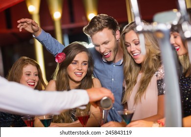 Drunk friends watching barman pouring cocktail at the nightclub