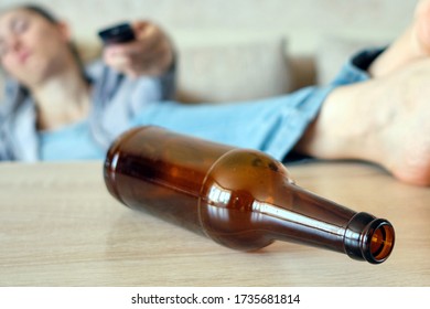 The Drunk Girl Lies On A Sofa Switching Channels On The TV, Legs On The Table Close Up.