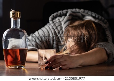 Drunk intoxicated woman sleeping near whiskey glass, female heavy drinker alcoholic passed out lying asleep after booze, alcoholism problem, alcohol addiction concept.