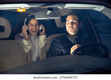 Drunk man driving car while woman listening to music