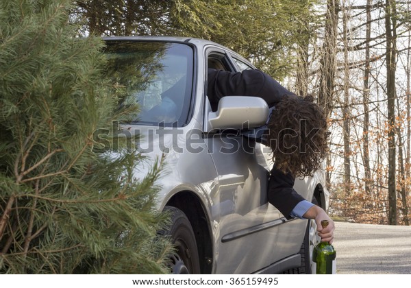 Drunk man hangs out of window holding wine\
bottle after driving car\
accident