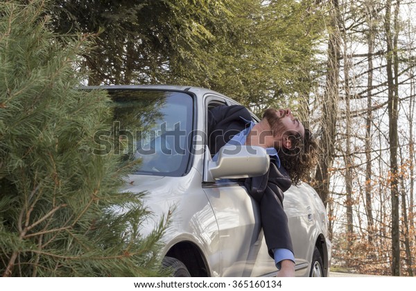 Drunk man hangs out of window holding wine\
bottle after driving car\
accident