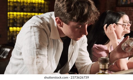 Drunk man leans on bar counter and looks into empty glass. Guy drinks strong alcohol to relieve tension and forget about problems - Powered by Shutterstock