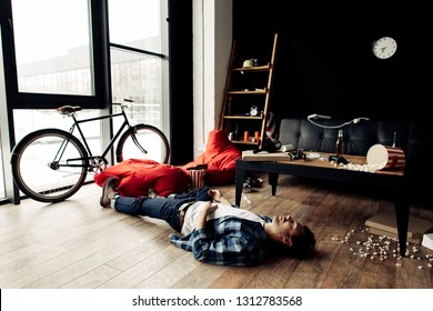 Drunk Man Lying On Floor In Messy Living Room After Party