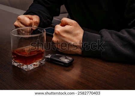 

Drunk man lying on the table with a glass of alcohol, car keys on the counter, drunk car driver, drowning sadness in a glass of whiskey, despair