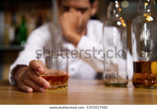 パブのバーに座り 右手にウィスキーグラスを持つ酔っ払いは 酒を飲み 頭痛を感じた後 もう一本手を頭に当てた アルコールのコンセプト の写真素材 今すぐ編集