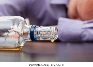Drunk Man Sleeping With Almost Empty Bottle Of Alcohol