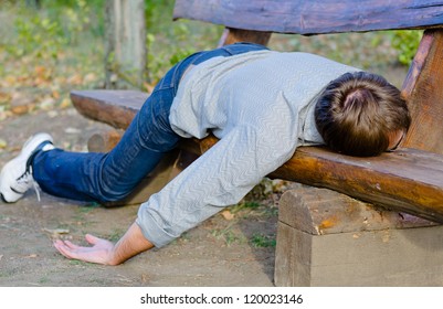Drunk man sleeping in park on wooden bench