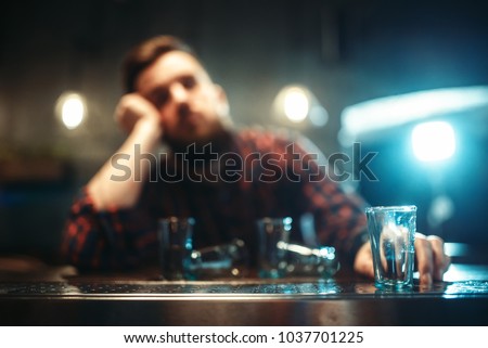 Drunk man sleeps at bar counter, alcohol addiction