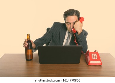 Drunk Persian Businessman Drinking Beer While Talking On Old Telephone At Work