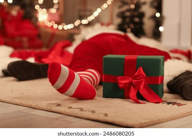 Drunk Santa Claus with gift box sleeping on carpet after party, closeup - Powered by Shutterstock