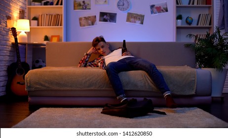 Drunk Teen Student Sitting On Sofa With Beer Bottle, Harmful Alcohol Addiction