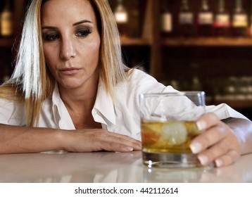 drunk woman alone in wasted and depressed face expression holding and looking thoughtful to scotch whiskey glass isolated at bar or pub in alcohol abuse and alcoholic housewife concept