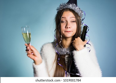 drunk woman in a festive cap holding champagne in hands