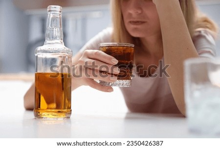 Drunk woman holding glass of whiskey and alcoholics alone