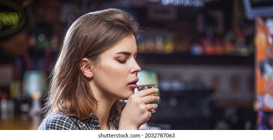 Drunk woman holding a glass of whisky or rum. Woman in depression. Young beautiful woman drinking alcohol. Scotch whiskey glass isolated at bar or pub in alcohol abuse and alcoholic concept.