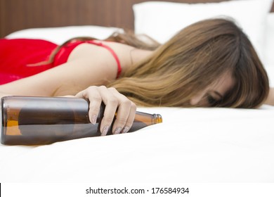Drunk woman on the bed  with bottle in hand