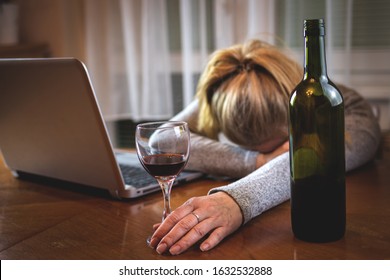 Drunk woman with open laptop sleeping on table after drinking alcohol. Red wine glass in female hand. Insomnia problem
