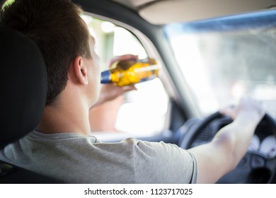 Drunk Young Driver Drinking A Bottle Of Alcohol During Driving The Car, Campaign Picture, Do Not Drink Alcohol When You Drive