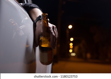 Drunk young man driving a car with a bottle of beer. Don't drink and drive concept. 