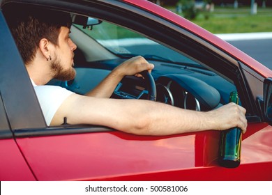 Drunk Young Man Driving A Car With A Bottle Of Beer. Don't Drink And Drive Concept. Driving Under The Influence. DUI, Driving While Intoxicated. DWI