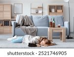 Drunk young woman lying on floor at home. Concept of alcoholism