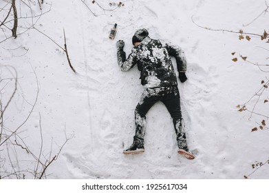 A drunken homeless and dirty man in a black coat lies, sleeps on his stomach on white snow in a frosty winter with a bottle of alcohol, strong whiskey. Photography, copy space.
