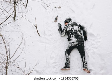 A drunken homeless and dirty man in a black coat lies, sleeps on his stomach on white snow in a frosty winter with a bottle of alcohol, strong whiskey. Photography, copy space.
