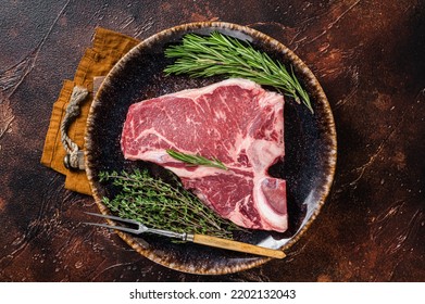 Dry Aged Raw Porterhouse Beef Meat Steak, Fresh T Bone On Rustic Plate With Spices. Dark Background. Top View.