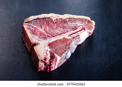 Dry Aged And Raw T Bone Steak Isolated On A Black Cutting Board