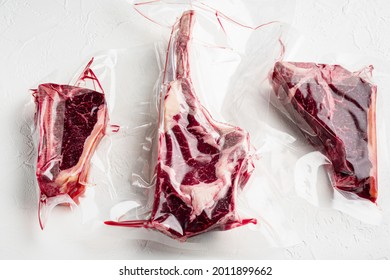 Dry Aged Steak In A Vacuum. Meat Products In Plastic Pack Set, Tomahawk, T Bone And Club Steak Cuts, On White Stone  Background