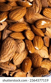 Dry almonds soaked in water on a rustic wooden background
				